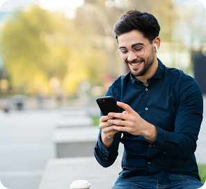 Man smiling at his phone outdoors